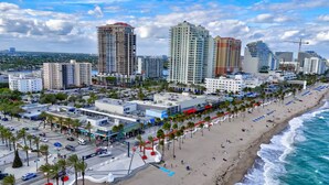 A coastal cityscape with high-rise buildings, a beach, and a promenade lined with palm trees. - Studio off Las Olas- Steps to the Beach (Fort Lauderdale)