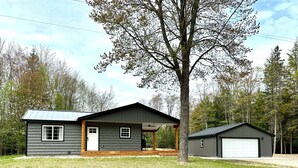 A two-story cabin with a porch, a garage, and a small deck.