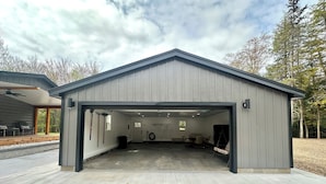 A covered garage with a concrete floor, a door, and a small office area with a desk and chair.