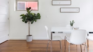 A modern dining area with a white table, white chairs, a potted plant, and two framed quotes on the wall. - North Beacon Hill Townhouse — 3 Bedrooms, Each with a Private En-Suite Bathroom (Seattle)