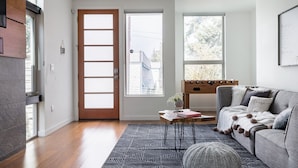 A modern living room with a sofa, a coffee table, and a door leading outside. - North Beacon Hill Townhouse — 3 Bedrooms, Each with a Private En-Suite Bathroom (Seattle)