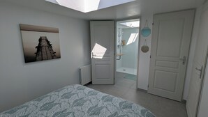 A bedroom with a skylight, a bed with a leaf-patterned bedspread, a wall-mounted picture, and two doors leading to other rooms. - La Maison d'Anita at Le Tilleul, 4 km from Etretat, ideal for families or friends. (Le Tilleul)