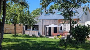A modern house with a wooden exterior, a patio with a table and chairs, and a well-maintained lawn. - La Maison d'Anita at Le Tilleul, 4 km from Etretat, ideal for families or friends. (Le Tilleul)