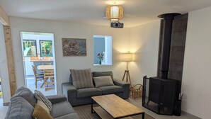 A modern living room with a sofa, a coffee table, a fireplace, and a dining area visible through an open door. - La Maison d'Anita at Le Tilleul, 4 km from Etretat, ideal for families or friends. (Le Tilleul)