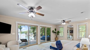 A spacious bedroom with a large bed, a ceiling fan, a TV, and a sliding glass door leading to a balcony with outdoor furniture. - Game Room, 3 Kings, Guest Suite, Lakefront (Mooresville)