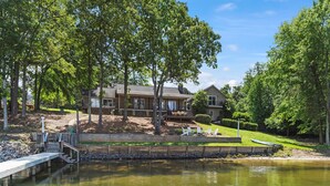 A lakeside property with a dock, a house with a deck, and a well-maintained lawn. - Game Room, 3 Kings, Guest Suite, Lakefront (Mooresville)