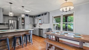 A modern kitchen with grey cabinets, stainless steel appliances, and a wooden island with stools. - Game Room, 3 Kings, Guest Suite, Lakefront (Mooresville)