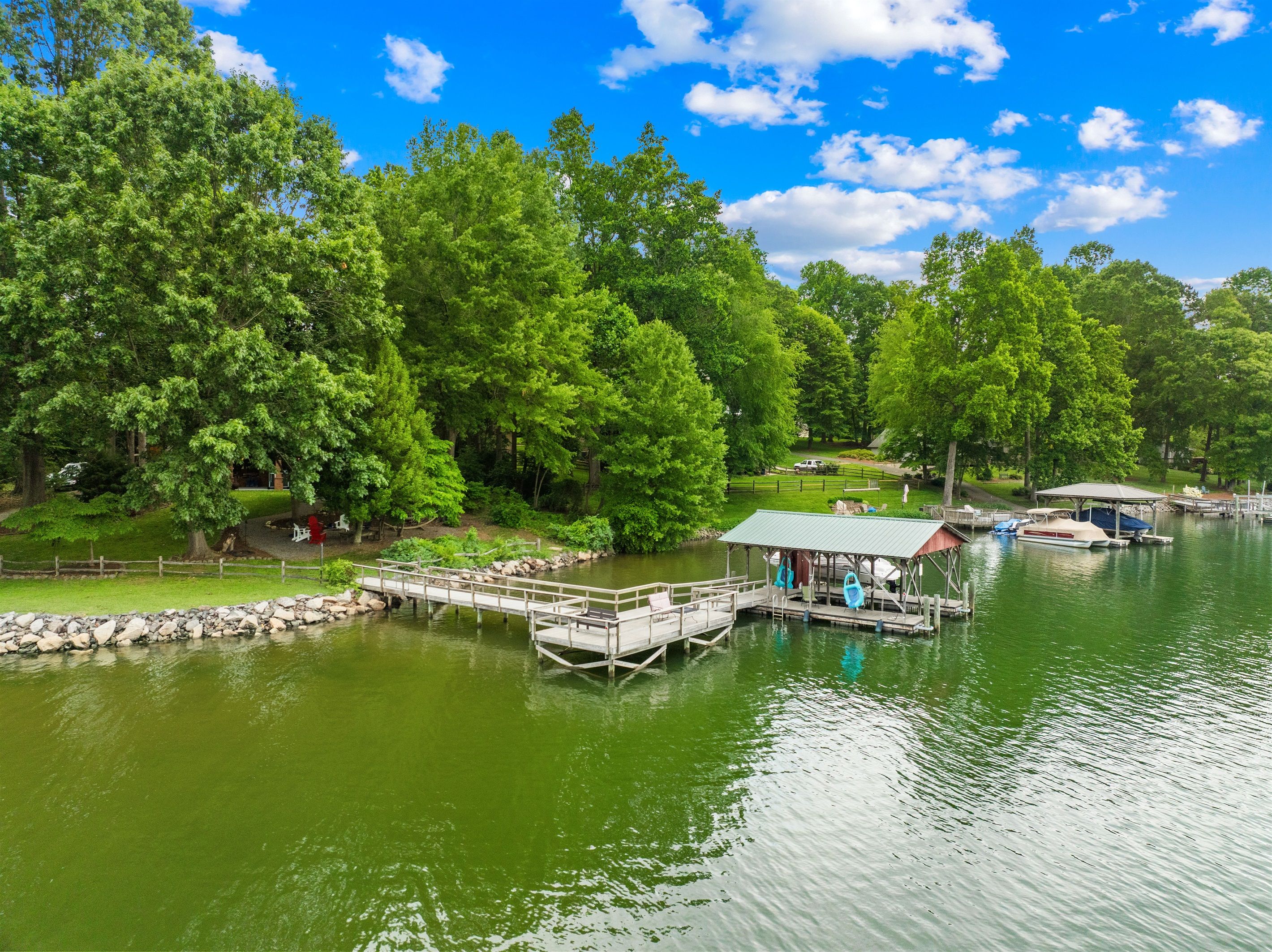 A lakeside dock with boats, a covered seating area, and lush greenery.