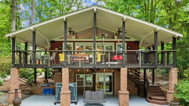 A two-story building with a covered patio, outdoor seating, and a fireplace. - Massive Dock • Firepit • Kayaks • Ping Pong (Mooresville)