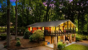 A two-story house with a deck, surrounded by trees and a well-maintained garden. - Massive Dock • Firepit • Kayaks • Ping Pong (Mooresville)