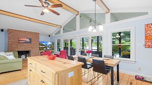 A spacious living area with a fireplace, a dining table with chairs, and a kitchen island. - Massive Dock • Firepit • Kayaks • Ping Pong (Mooresville)