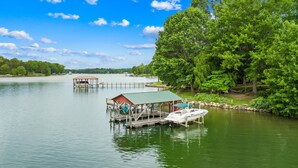 A lakeside dock with a covered seating area and a boat. - Massive Dock • Firepit • Kayaks • Ping Pong (Mooresville)