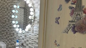 Un baño con espejo, lavamanos y decoración en la pared.