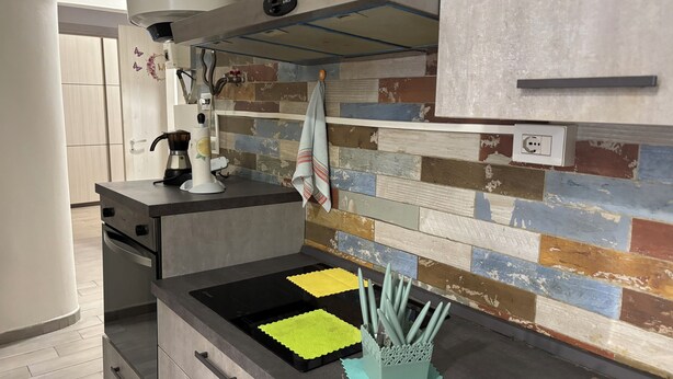 Una cocina con diseño moderno, que cuenta con un horno empotrado, una cafetera y una variedad de utensilios de cocina.