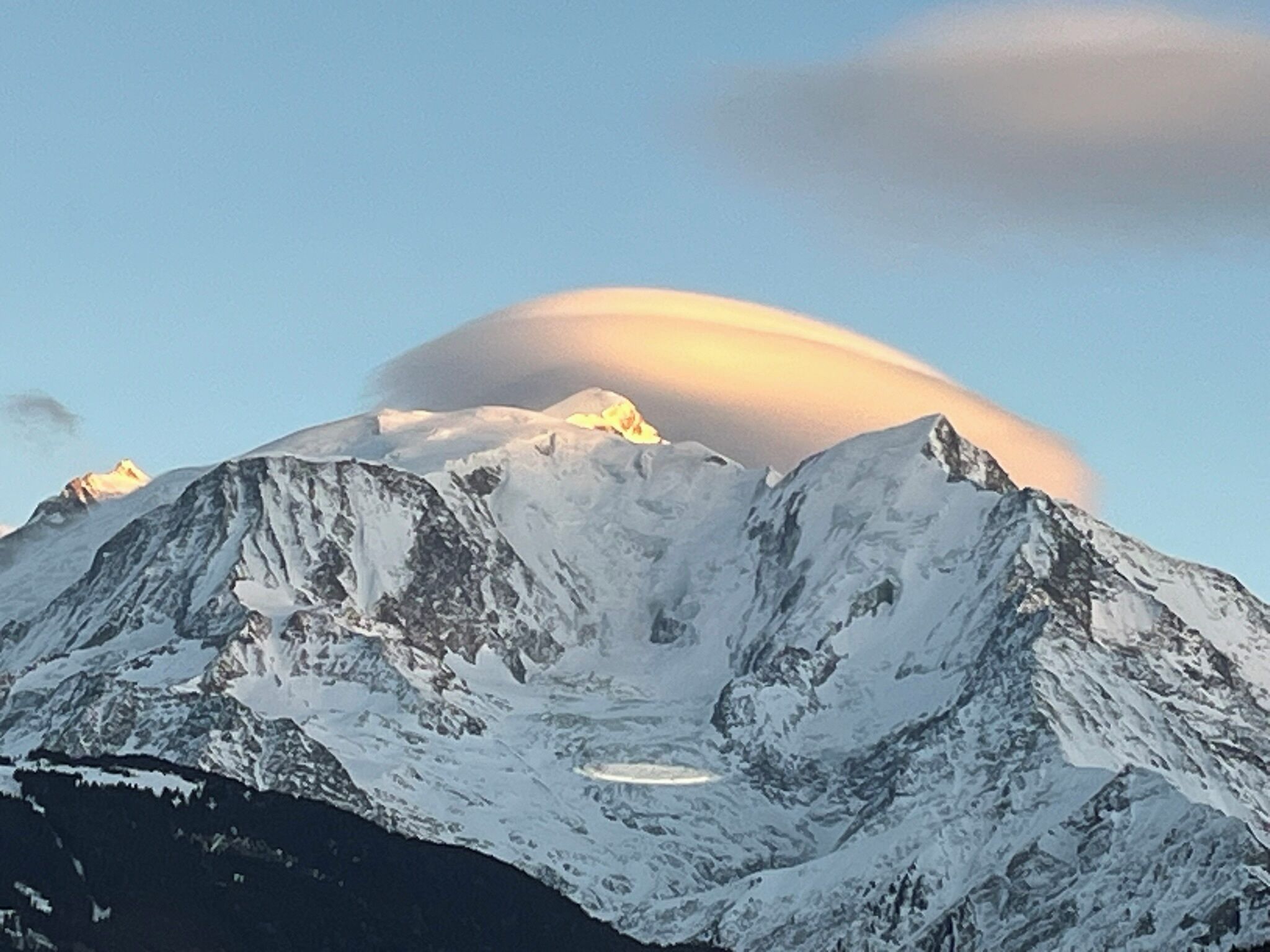 Cordillera nevada con cielo despejado y una luna creciente.