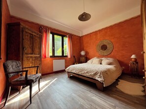 Ein Schlafzimmer mit einem hölzernen Bett, einem Sessel, einem Heizkörper, einem Globus und einer Wandweberei.