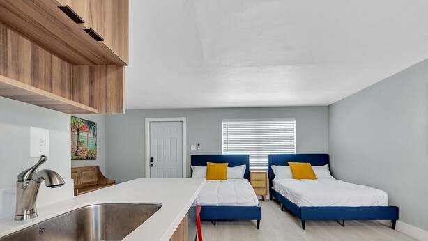 Ein modernes Schlafzimmer mit zwei Betten, einer Küchenzeile und einer Tür.