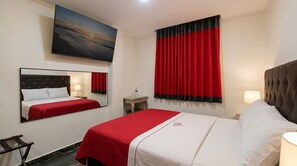 A hotel room with a bed, a bedside table, a mirror, a window with red curtains, and a painting on the wall. - HOSTAL PARIS 1 (Lima)
