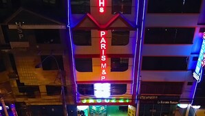 En bygning med flere etager og et iøjnefaldende neonlys med teksten 'H S PARIS M & P'.