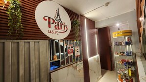 Une devanture de magasin sur le thème de Paris, avec une enseigne représentant la Tour Eiffel, une vitrine exposant des produits et un mur décoré de lambris en bois.