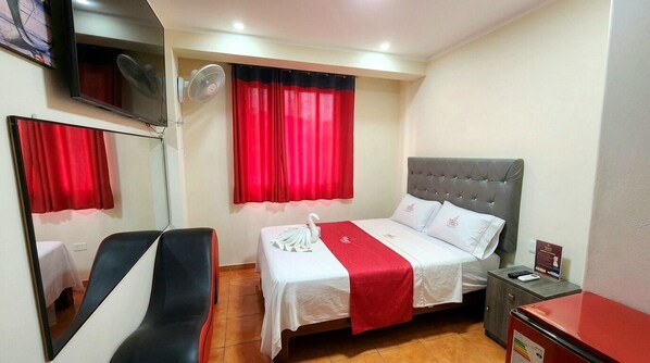 A hotel room with a bed, a chair, a TV, and a desk with a computer. - HOSTAL PARIS 1 (Lima)