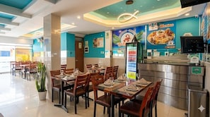 A restaurant with tables set for dining, a counter with a menu, and a beverage dispenser. - HOSTAL PARIS 1 (Lima)