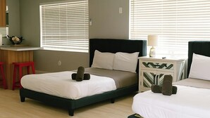 A hotel room with two beds, a desk, and a chair.