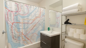 A bathroom with a large map on the wall, a sink, a mirror, and shelves with toiletries. - NYC Studio with Private Bathroom & Kitchenette (New York)