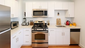 A modern kitchen with stainless steel appliances, white cabinetry, and a wooden countertop. - NYC Studio with Private Bathroom & Kitchenette (New York)