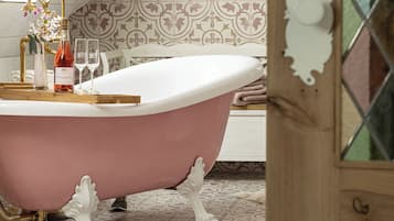 Un baño de estilo vintage con una bañera independiente, un perchero para toallas y una zona de ducha decorativa.
