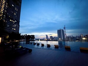 A rooftop pool with lounge chairs and a cityscape view at dusk. - M Vertica KL City by Dynasty (Kuala Lumpur)