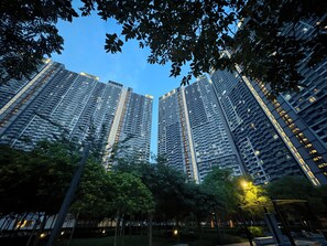 A high-rise residential building with multiple floors, surrounded by trees and a well-maintained park area.