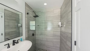 A modern bathroom with a glass-enclosed shower, a white sink, and a large mirror.