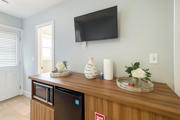 Una cocina equipada con microondas, refrigerador y un televisor de pantalla plana montado en la pared.