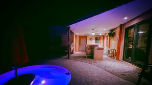 Een terras met een hottub, een tafel en een bar.