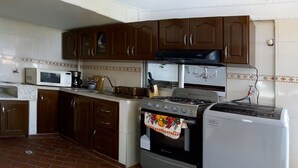 Una cocina compacta con gabinetes marrones, un microondas, una estufa y un refrigerador.