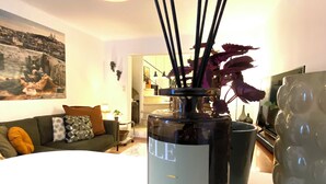 A room with a table holding a bottle labeled 'ELE GANT' and a vase with black sticks and purple leaves. - Typical house in the historic center of the Arles bullring (Arles)