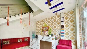 A reception area with a marble reception desk, a red sofa, a pink sofa, and a staircase with red decorations. - Hotel Tirupati Ujjain  (Ujjain)