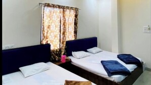 A hotel room with two beds, each with a headboard and pillows. The room has a modern ceiling design with circular patterns and recessed lighting. - Hotel Tirupati Ujjain  (Ujjain)