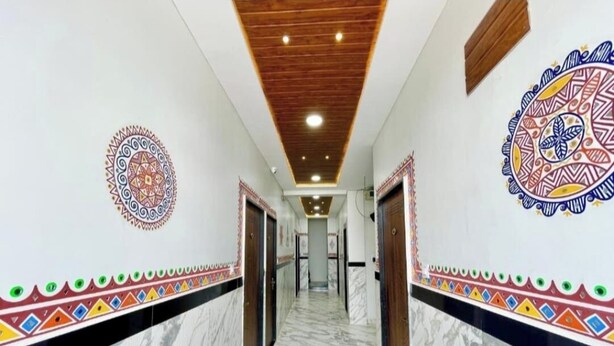 A hallway with marble flooring, wooden ceiling, and patterned wall decorations. - Hotel Tirupati Ujjain  (Ujjain)