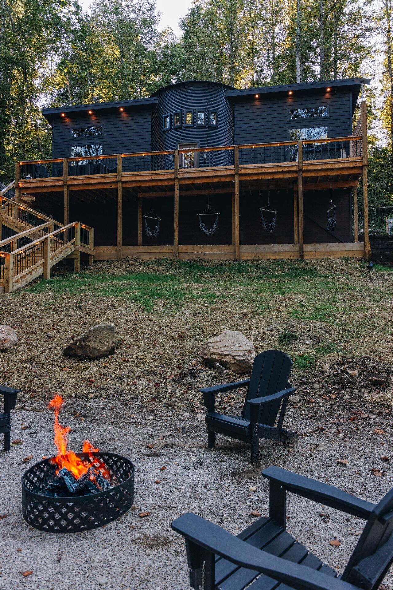 A cabin with a deck, outdoor seating, and a fire pit.