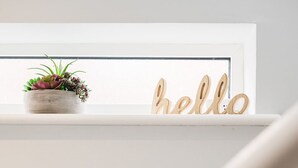 A white shelf with a small potted plant and wooden 'hello' letters. - The Nook, Fairview, Cheltenham Town Centre - Parking & Garden (Cheltenham)