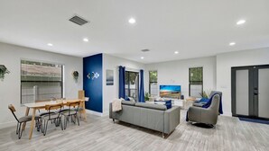 Ein modernes Wohnzimmer mit Essbereich, grauem Sofa und grauem Sessel.