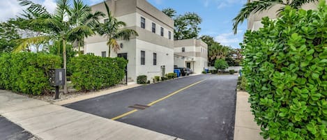A modern building with a flat roof, large windows, and a parking lot.