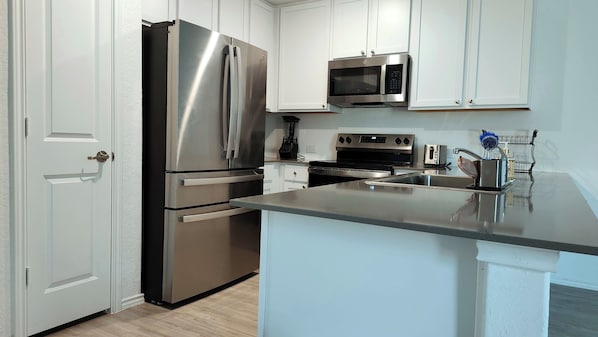 A modern kitchen with stainless steel appliances, white cabinetry, and a central island.