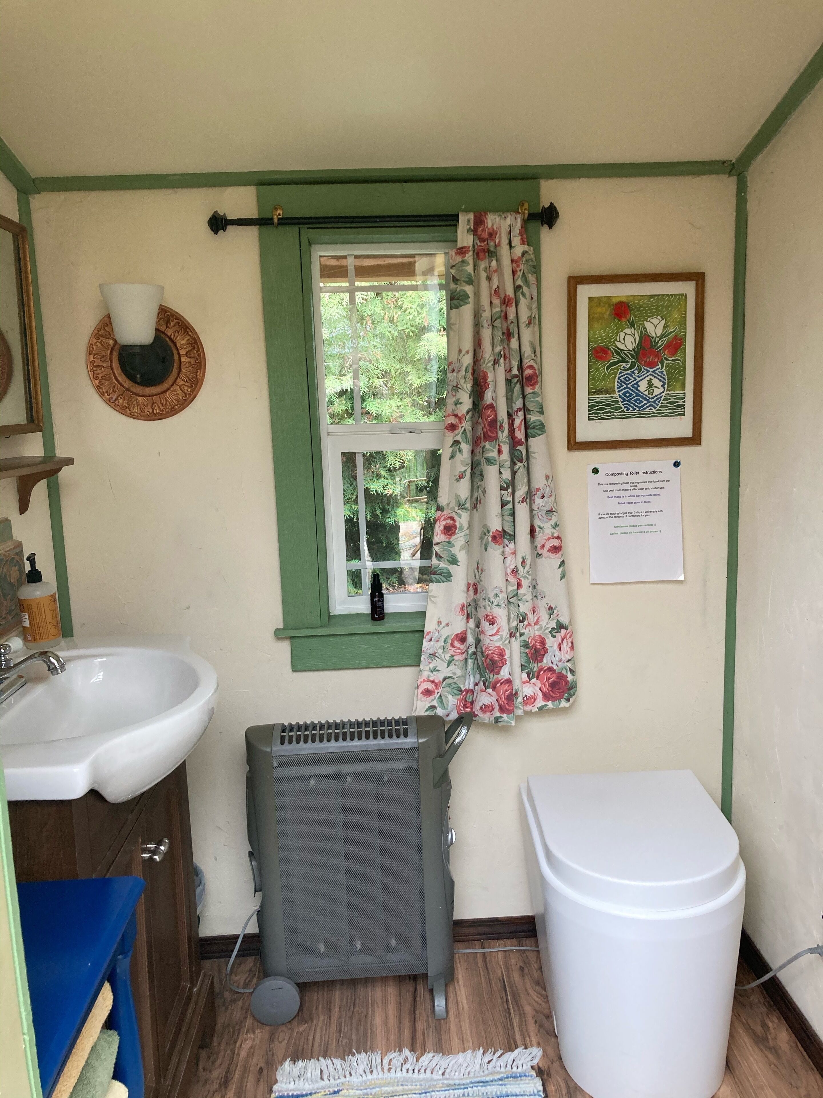 A small bathroom with a sink, a toilet, a radiator, and a window with curtains.