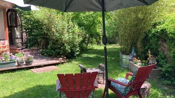 A patio area with two red Adirondack chairs, a table, and a large umbrella.