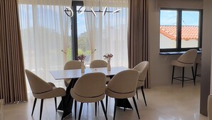 Un comedor moderno con una mesa y sillas, ventanas grandes con cortinas y vistas al exterior.