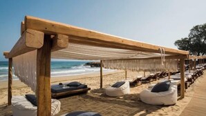 Zona relax a la platja amb pèrgoles de fusta, butaques de borró i gandules.