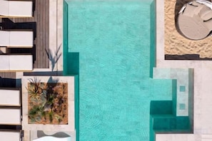 An aerial view of a swimming pool with adjacent lounge chairs and a small garden area.